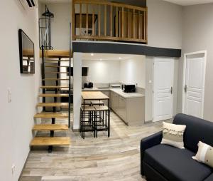 sala de estar con sofá, cocina y escalera en studio meublé du bourg en Puymiclan