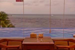 a cat sitting on a table in front of the ocean at Season Paradise in Thulusdhoo
