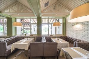 a restaurant with couches and tables and windows at Optima Collection Aquadar in Manʼkivka
