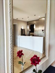 a mirror on a wall with red flowers in a vase at Hotel Ciudad de Navalcarnero in Navalcarnero