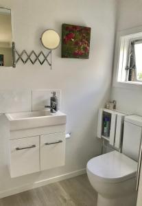 a white bathroom with a toilet and a sink at Bar Harbor in Papamoa