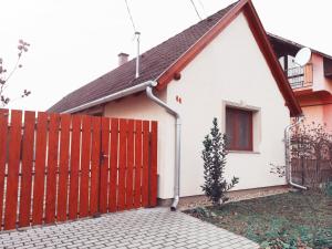 een wit en rood huis met een rode poort bij Napvirág Vendégház in Keszthely