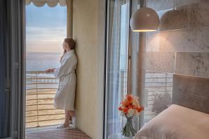 
a woman standing in front of a window with a vase of flowers at AmbientHotels Panoramic in Rimini
