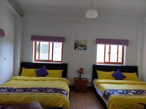 1 Schlafzimmer mit 2 Betten mit gelben und blauen Kissen in der Unterkunft Jinsha Haiyunbian I Homestay in Insel Nangan