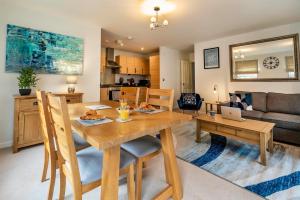 a kitchen and living room with a wooden dining room table at The Augustine - Modern two Bed Ground floor apartment with parking in Canterbury
