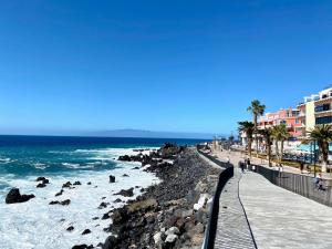 a beach with people walking on the sand and the ocean at Casa del Mar in Playa de San Juan