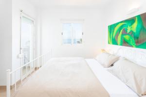 a white bedroom with a white bed and a painting at Higuerón Rental Marítimo Romar C in Fuengirola