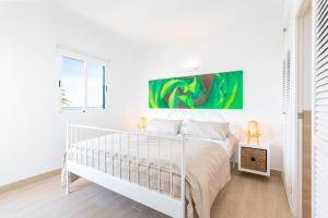 ein weißes Schlafzimmer mit einem Bett und einem Gemälde an der Wand in der Unterkunft Higuerón Rental Marítimo Romar C in Fuengirola