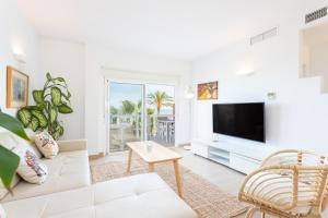 a living room with a white couch and a tv at Higuerón Rental Marítimo Romar C - Managed by Higuerón Resort in Fuengirola