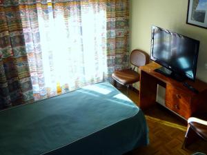 a bedroom with a bed and a tv and a window at Hotel Can-Vic in Guadalajara