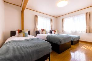 two beds in a room with windows at Ma Maison Mt. Fuji Kawaguchiko in Fujikawaguchiko