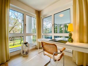 ein Büro mit einem Schreibtisch und einem Stuhl vor den Fenstern in der Unterkunft Villa Seepark - Ferienwohnung 7 in Heringsdorf