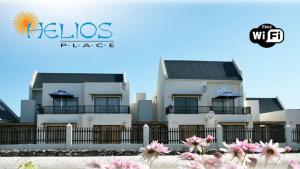 a white building with a fence and pink flowers at Little Greece - Beach House Apartment by Mykonos in Langebaan
