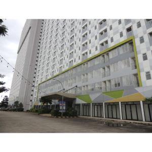 a large white building with a parking lot in front of it at Reva Room on Gunung Putri Square Apartment in Bogor