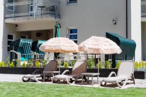 three chairs and umbrellas in front of a building at Villa Solaris in Pobierowo