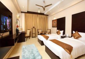 a hotel room with two beds and a flat screen tv at Five Elements Hotels The Claire in Gurgaon