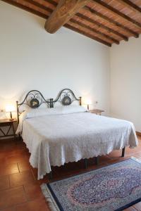 1 dormitorio con 1 cama con colcha blanca y 2 lámparas en La Locanda Cuccuini en Cavriglia