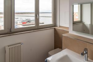ein Badezimmer mit einem Waschbecken und zwei Fenstern in der Unterkunft Ferienwohnung Kiek ut in Barth