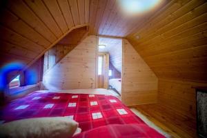 Cette chambre en bois comprend un lit rouge. dans l'établissement Kedra Village, à Kédra