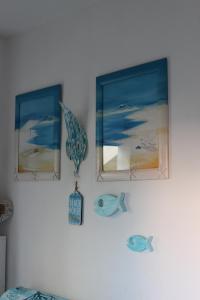 un mur avec deux photos de la plage et une horloge dans l'établissement BEACH HOUSE STEFI, à Golfo Aranci