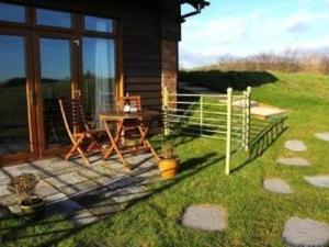 a house with a patio with a table and a fence at Poachers Hut - Captivating 1-bed Cottage Shorwell in Shorwell