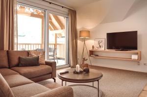 a living room with a couch and a tv at die Tauplitz Lodges - Alm Lodge A13 by AA Holiday Homes in Tauplitz