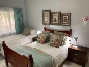 a bedroom with two beds and a lamp on a table at Jelani Guest House in White River