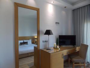 - une chambre avec un lit et un bureau avec un miroir dans l'établissement Hotel Alexandros, à Anchialos