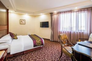 una camera d'albergo con letto, scrivania e TV di Beijing Commercial Business Hotel a Pechino