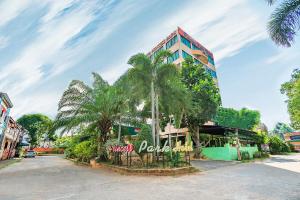 a building with palm trees in front of a street at Princess Park Hotel in Surat Thani