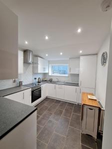 una cucina con armadietti bianchi e pavimento piastrellato di Bruxie Holiday Cottages - Honeysuckle Cottage a Maud