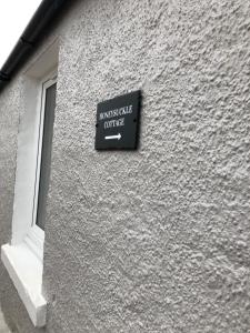 a sign on the side of a building with a window at Bruxie Holiday Cottages - Honeysuckle Cottage in Maud