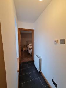 a hallway leading to a bedroom with a bed at Bruxie Holiday Cottages - Honeysuckle Cottage in Maud