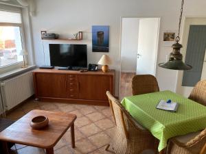 a living room with a table and a television at Hellinghaus FeWo 1 Wellenreiter in Wyk auf Föhr