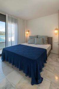 a bedroom with a large bed with a blue blanket at Playa Vista Mar Duplex in Port de la Selva