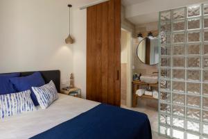 a bedroom with a blue bed and a glass wall at Playa Vista Mar Duplex in Port de la Selva