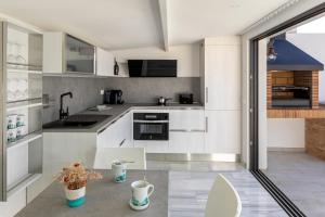 a kitchen with white cabinets and a table at Playa Vista Mar Duplex in Port de la Selva