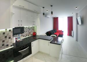 une cuisine avec des placards blancs et un comptoir noir dans l'établissement Elite apartments in the center of Lviv, à Lviv