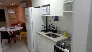 een keuken met een witte koelkast en een tafel bij GUARAJUBA - Apartamento novíssimo 2 quartos - 170 m da praia GUARAJUBA - Apartamento novíssimo 2 quartos - 170 m da praia in Guarajuba