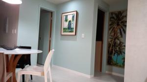 a dining room with a white table and a white chair at GUARAJUBA - Apartamento MÁXIMO 4 PESSOAS -2 quartos - 170 m da praia in Guarajuba