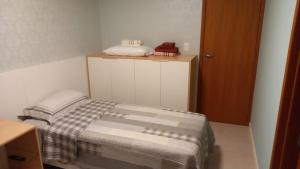 a small bedroom with a bed and a wooden cabinet at GUARAJUBA - Apartamento MÁXIMO 4 PESSOAS -2 quartos - 170 m da praia in Guarajuba