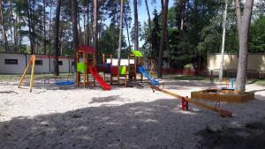 um parque infantil com muitos baloiços coloridos diferentes na areia em Villa Kama em Skorzęcin