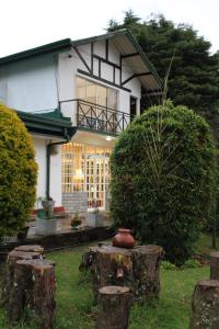 una casa con un tronco de árbol delante de ella en Blossomwell Bungalow, en Nuwara Eliya