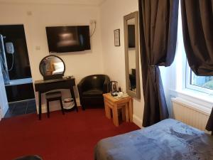 um quarto com uma cama, um espelho e uma cadeira em Maridon House em Oban