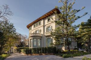 uma grande casa branca com uma árvore em frente em Hotel Boutique Mirlo Barcelona em Barcelona