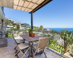 Villa del Mar - "Luxurious en-suite bedroom with lounge and stunning sea view balcony in Bantry Bay" في كيب تاون: طاولة وكراسي خشبية على شرفة مع المحيط