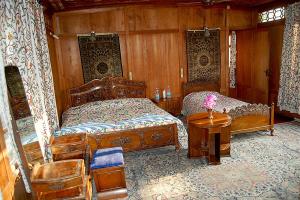 a bedroom with two beds and a table at Jacqueline houseboat in Srinagar