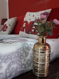 złota waza z kwiatami na stole obok łóżka w obiekcie Buze Luxury Suite w mieście Ostuni