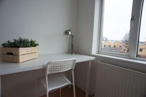 einen weißen Schreibtisch mit einem Stuhl neben einem Fenster in der Unterkunft Tooting Bec Rooms by DC London Rooms in London