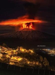 un volcán con una ciudad delante de él por la noche en Holiday Home Gionny & Mary, en Taormina